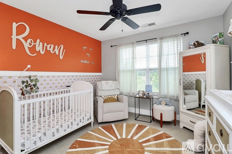 A baby nursery with a white crib and a white chair.