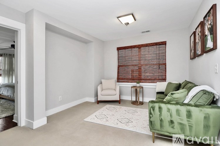 A living room with a green couch and a red window blind.