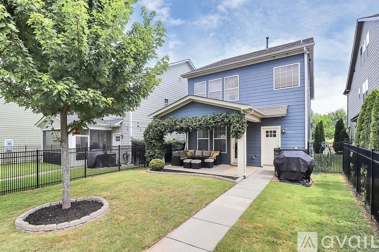 A blue house with a tree in the front yard.