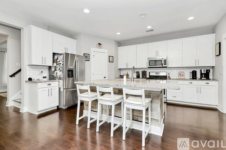 A kitchen with white cabinets and a wooden floor.