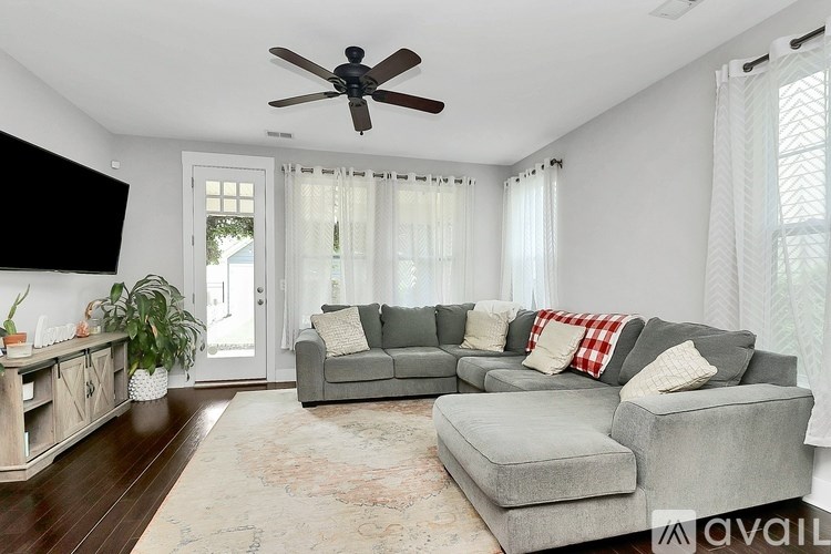 A living room with a grey couch and a ceiling fan.