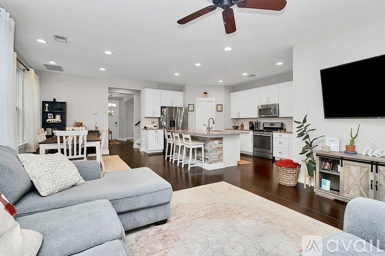 A living room with a grey sofa and a white dining table.