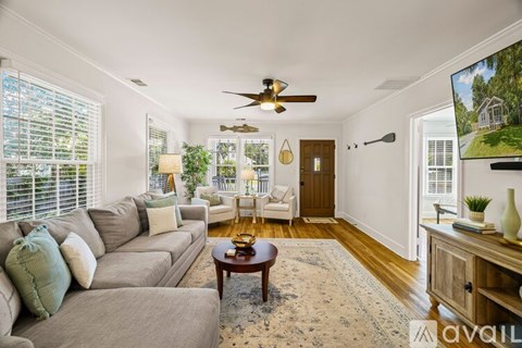 A living room with a grey couch, a wooden table, and a ceiling fan.