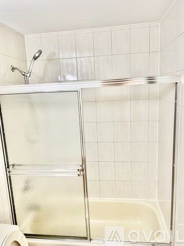 A white tiled bathroom with a glass shower door.