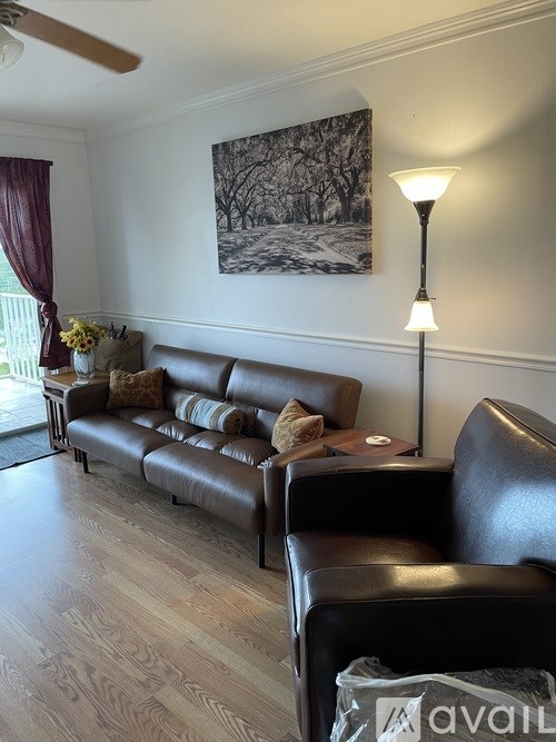 A living room with a brown leather couch and a painting on the wall.