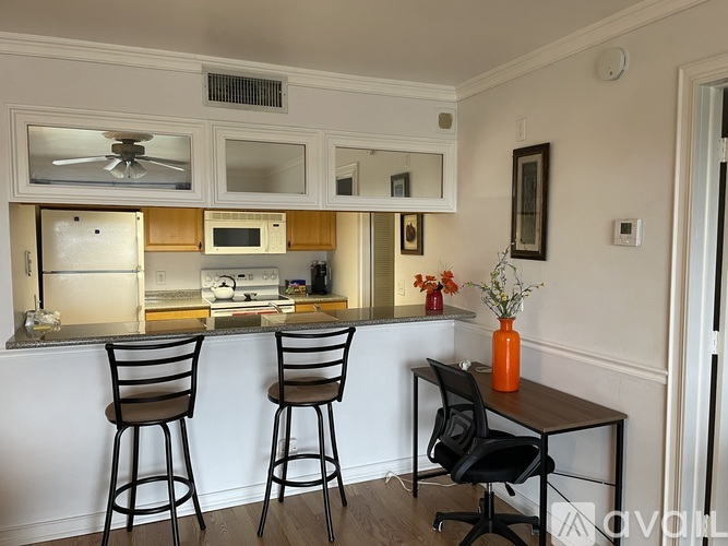 A black chair is in front of a table with a yellow vase on it.
