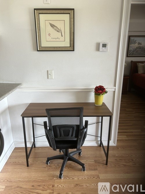A black chair is in front of a table with a yellow vase on it.
