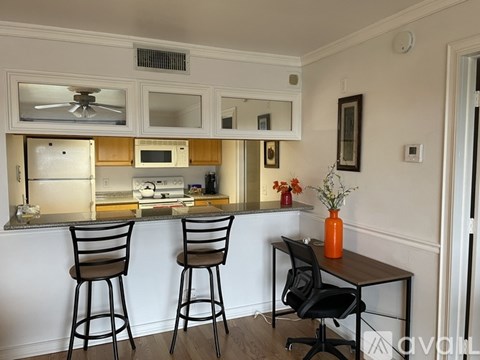 A black chair is in front of a table with a yellow vase on it.