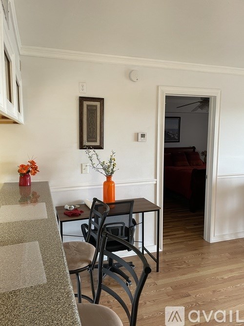 A kitchen with a table and chairs and a vase with flowers on the table.