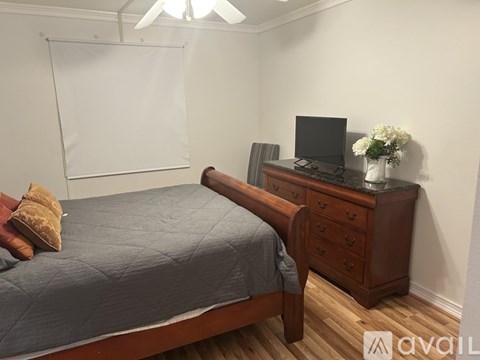 A bedroom with a bed, a dresser with a television and a whiteboard on the wall.