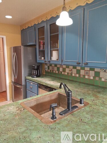 A kitchen with blue cabinets and a checkered backsplash.