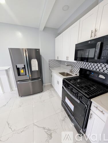 A kitchen with a black stove top oven and a silver refrigerator.