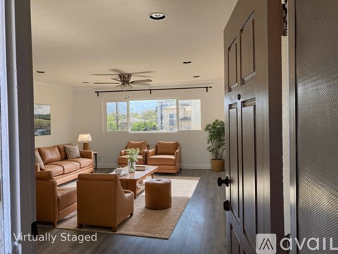 A living room with a brown sofa and a ceiling fan.