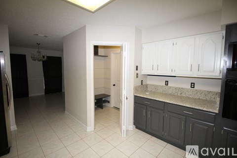 A kitchen with white cabinets and a black refrigerator.