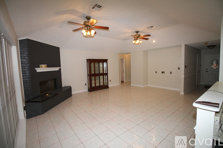 A spacious living room with a fireplace and a ceiling fan.
