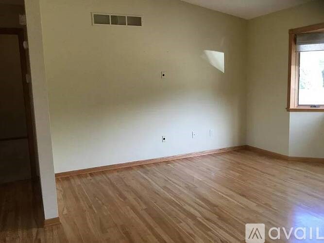 Empty room with wooden flooring and a window.