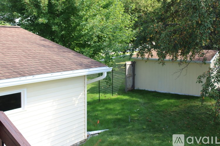 A white house with a brown roof and a green lawn.