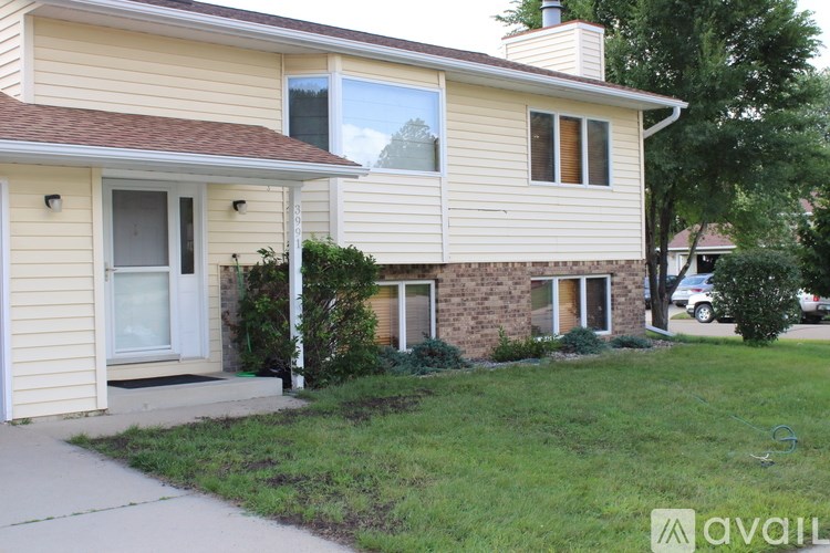 A house with a beige siding and a brown roof with a chimney.
