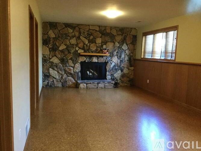 A stone fireplace in a room with wood paneling.
