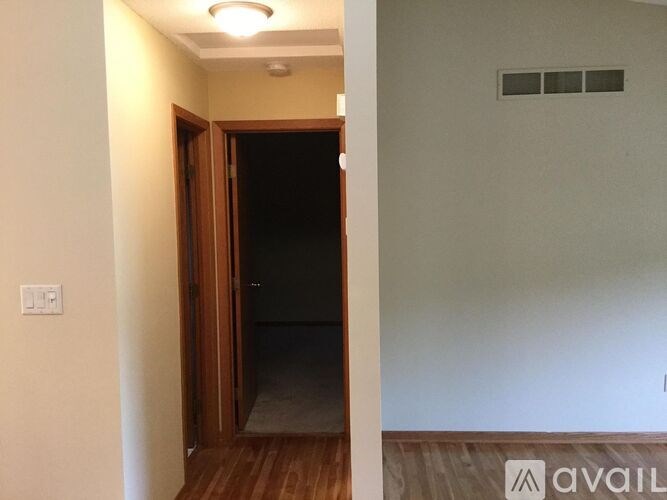 A room with a wooden door and a light switch on the wall.