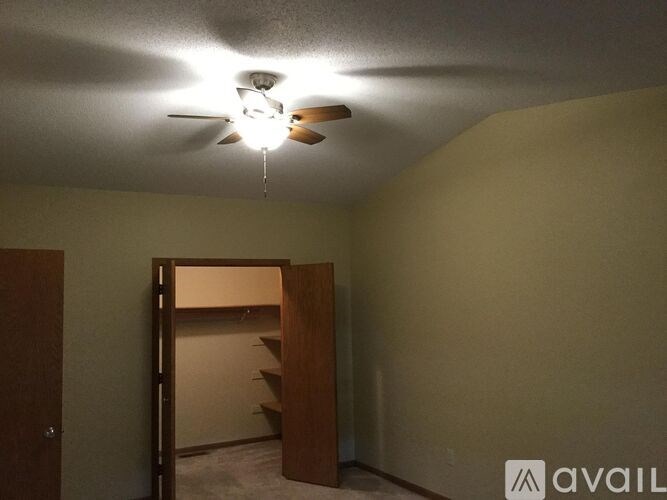 A room with a ceiling fan and a doorway leading to another room.