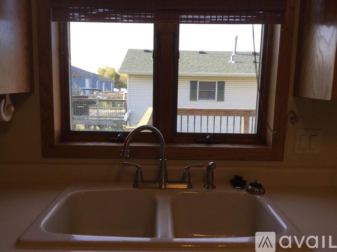 A bathroom sink with a window overlooking a house.