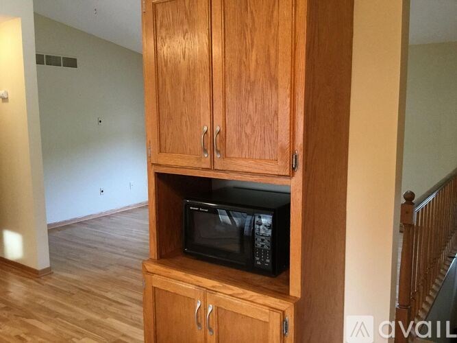 A black microwave is sitting on a wooden cabinet.