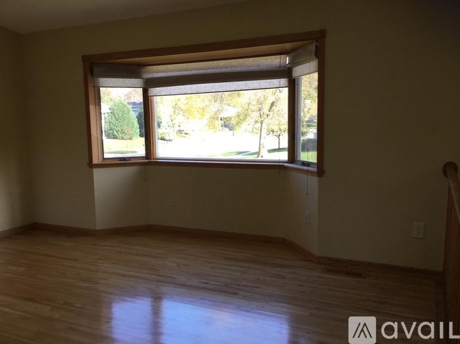 A room with a large window and wooden flooring.