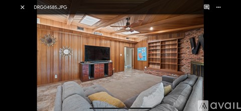 A living room with a grey sofa and a wooden wall.
