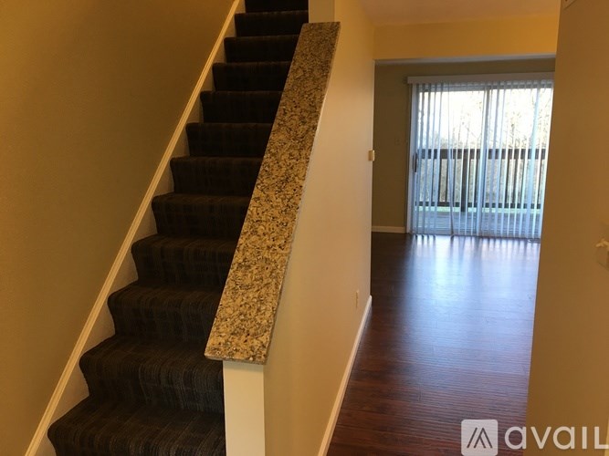 A staircase with a granite railing leads to a bright room with a window.
