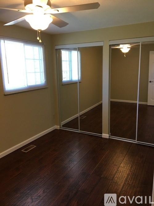 A room with a ceiling fan and sliding glass doors.