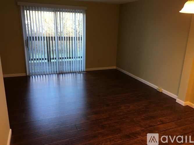 A room with wooden flooring and a window with blinds.