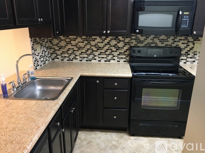 A kitchen with black cabinets and a black oven.