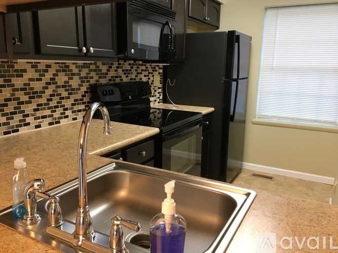 A kitchen with a black refrigerator and a black stove top oven.