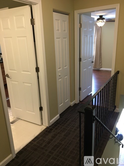 A hallway with a black railing and two white doors.