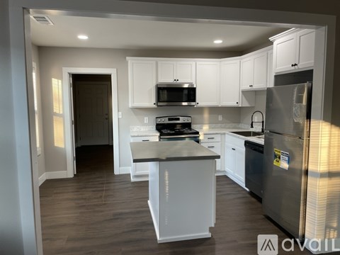 A kitchen with white cabinets and a stainless steel refrigerator.