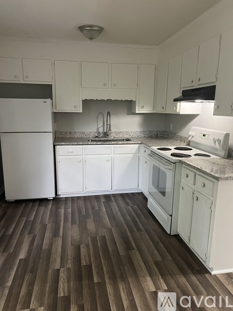 A kitchen with white appliances and wooden floors.