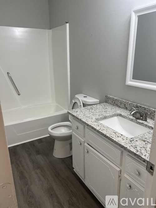 A bathroom with a toilet, sink, and mirror.