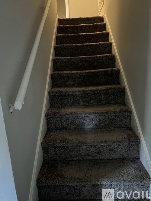 A staircase with a carpeted runner and white walls.
