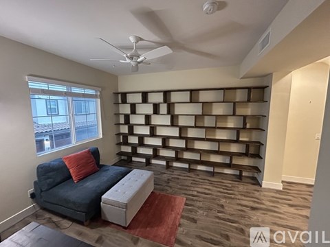 A living room with a blue couch and a fan on the ceiling.