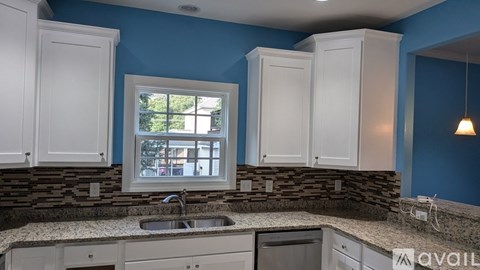 A kitchen with white cabinets and a stone backsplash.