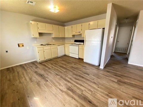 A kitchen with white appliances and wooden floors.