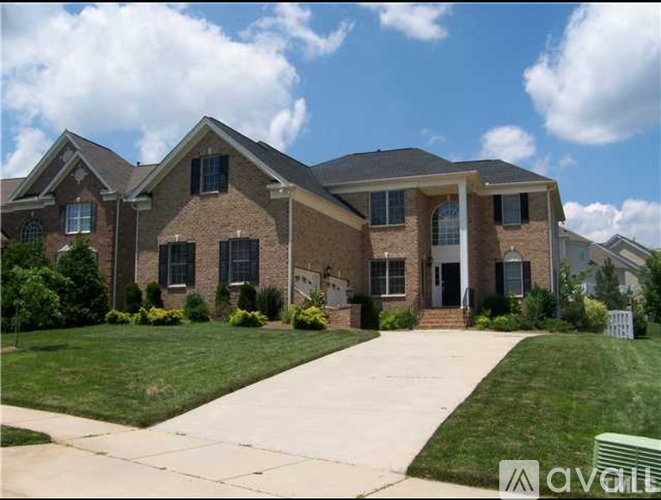 A large brick house with a front yard and a driveway.