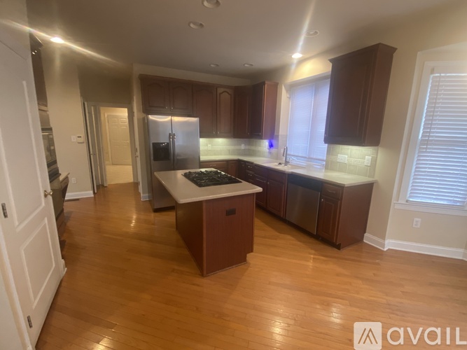 A room with a wooden floor and a large window with blinds.
