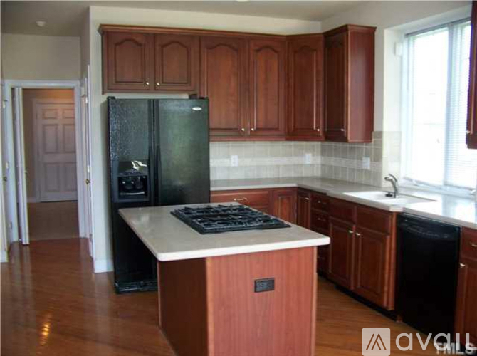 A kitchen with wooden cabinets and a black fridge.