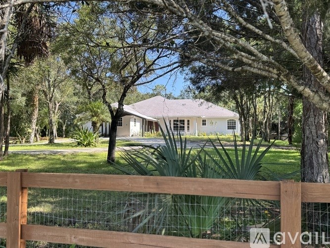 A house is surrounded by a fence and trees.