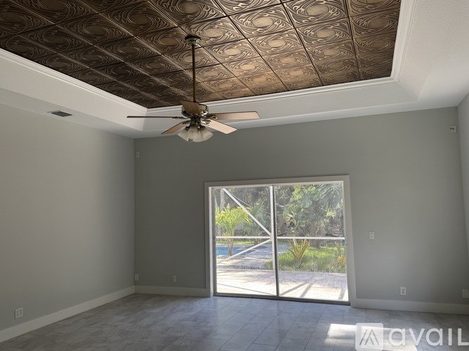 A room with a ceiling fan and sliding glass doors.