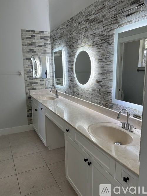 A bathroom with a stone wall and two sinks.