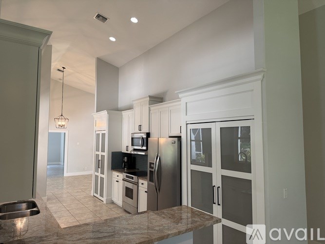 A kitchen with white cabinets and a refrigerator.