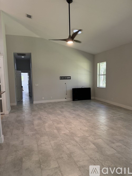 A room with a ceiling fan and a black box on the floor.